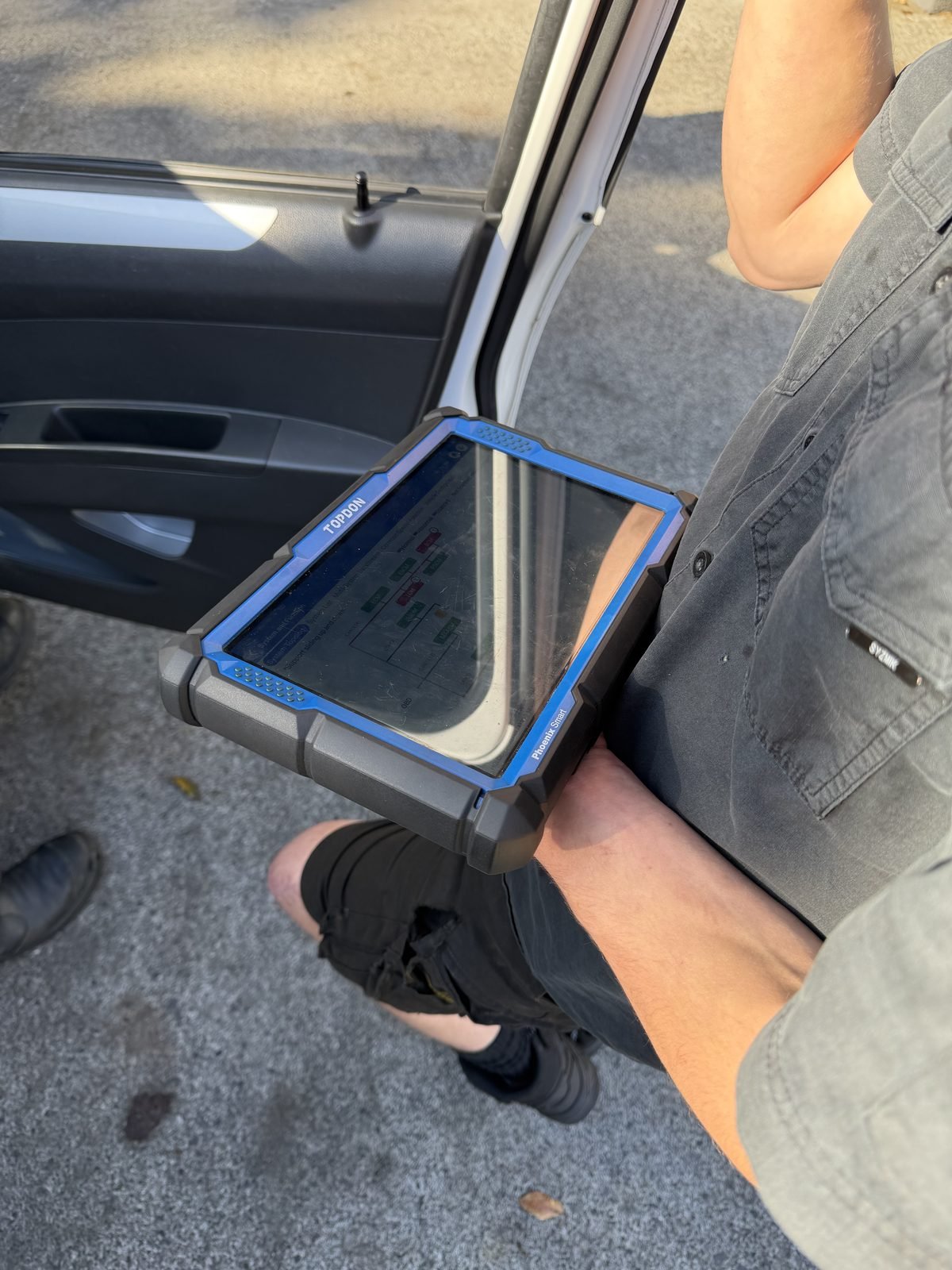 SuperVolt technician running diagnostics on a vehicle on-site with a TOPDON scan tool